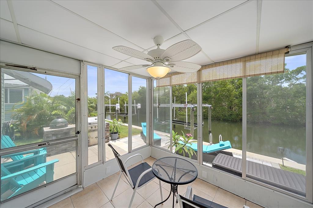 A sunroom with tile floors, a ceiling fan, and large windows overlooking a canal — 192 BIMINI DRIVE, PALMETTO, FL