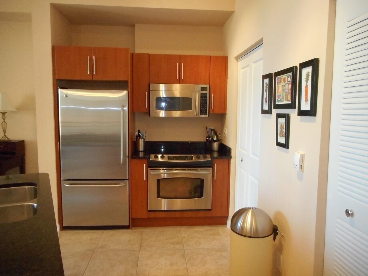 A kitchen features stainless steel appliances, wood cabinets, and dark countertops on a tiled floor — 600 S Dixie Highway # 452, West Palm Beach FL 33401, WEST PALM BEACH, FL