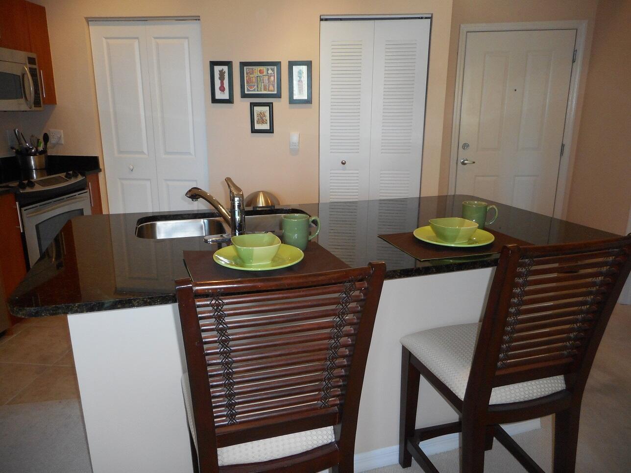 A kitchen island with a sink and two place settings sits in front of white doors — 600 S Dixie Highway # 452, West Palm Beach FL 33401, WEST PALM BEACH, FL