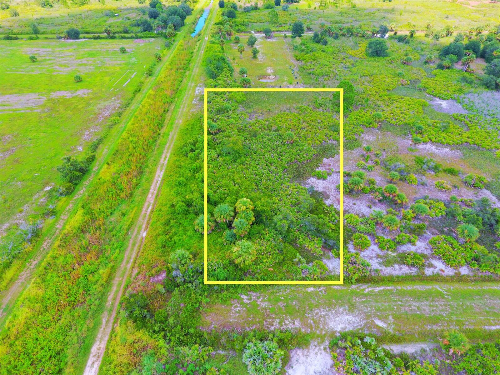 An aerial view shows a rectangular plot of land outlined in yellow amidst grassy terrain — 21591 NW 282nd Street, Okeechobee FL 34972, OKEECHOBEE, FL