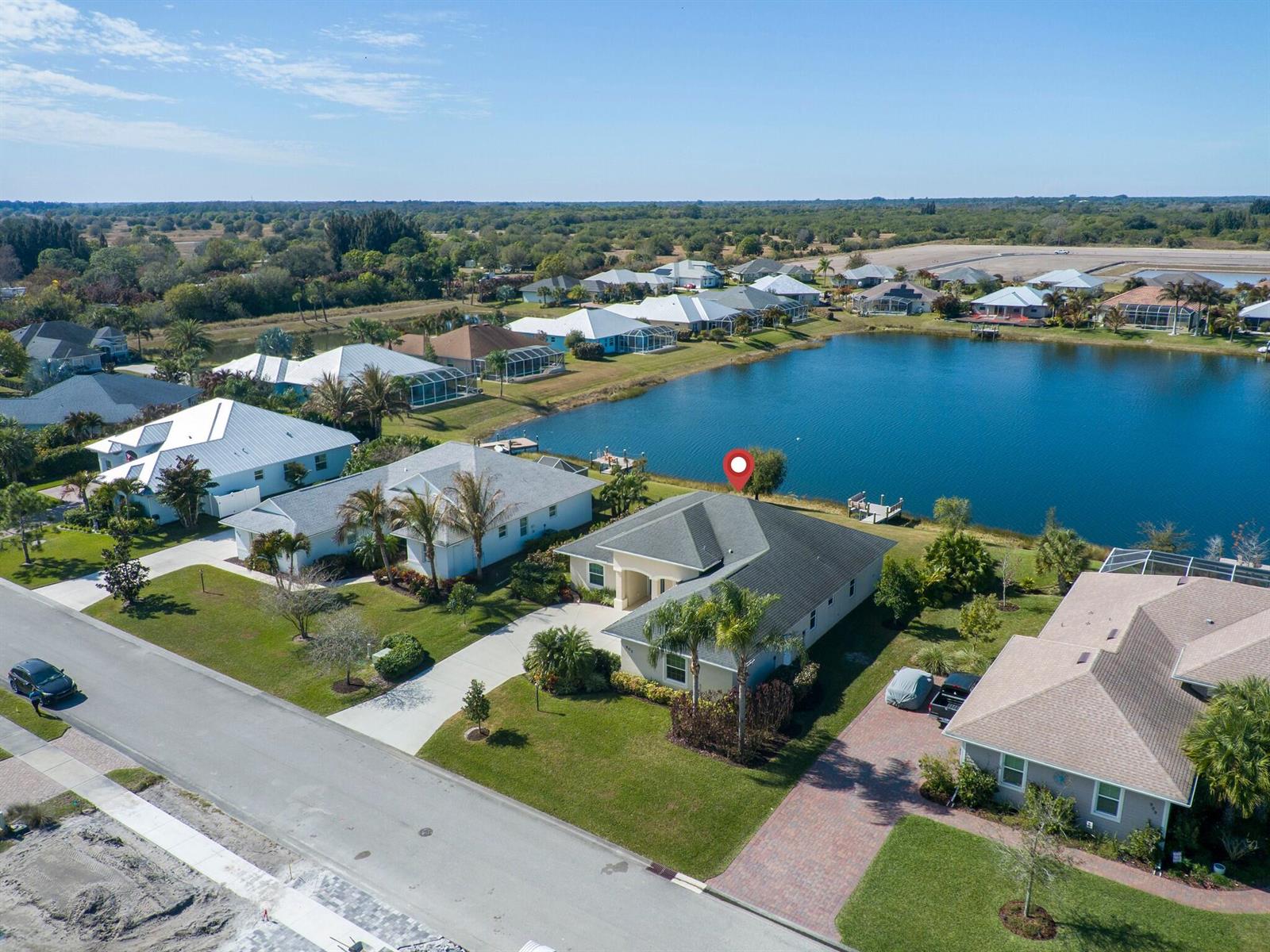 An aerial view shows a suburban house with a dark roof situated beside a lake — 907 Yearling Trail, Sebastian FL 32958, SEBASTIAN, FL