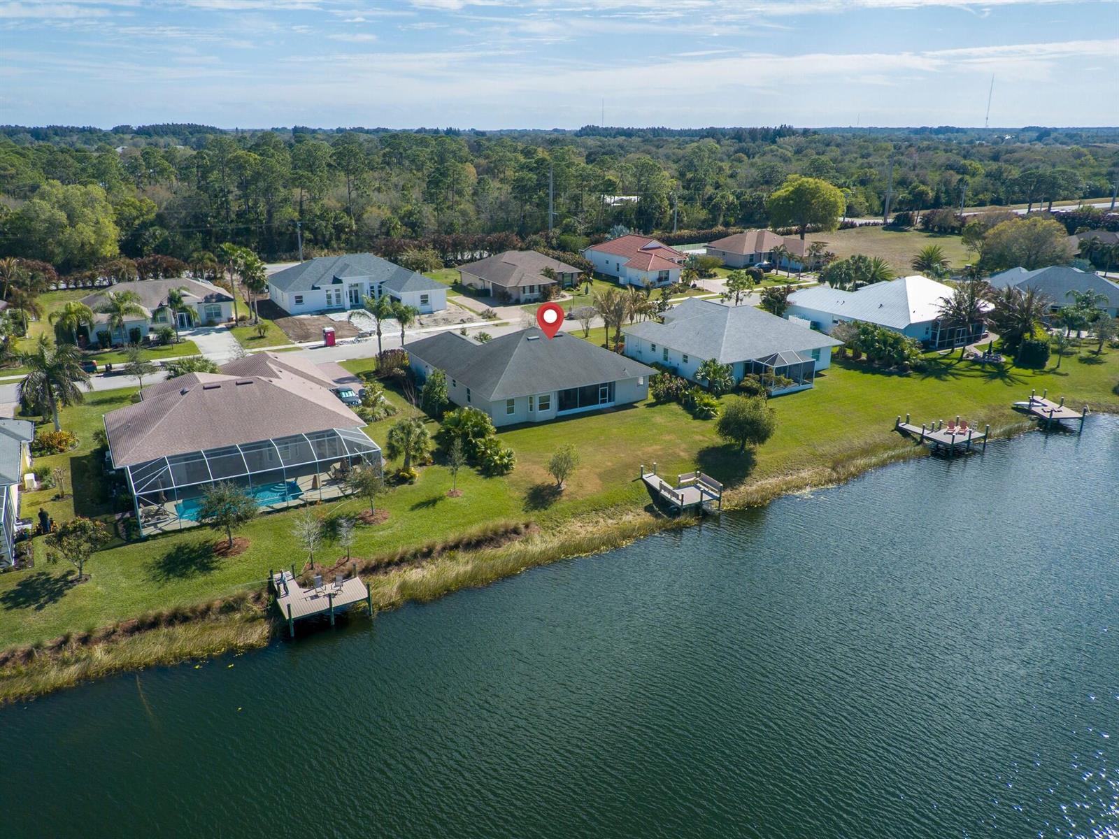 An aerial view shows a residential neighborhood with houses along a lake and private docks — 907 Yearling Trail, Sebastian FL 32958, SEBASTIAN, FL