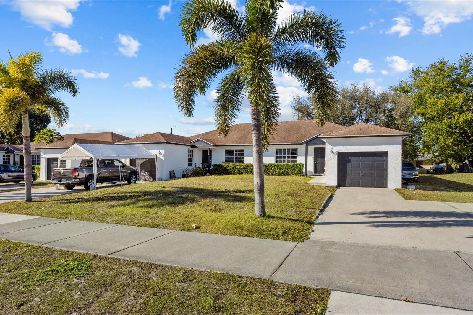 A single-story white house with a brown roof, two driveways, and two palm trees — 2593 SE Indian Street, Stuart FL 34997, STUART, FL