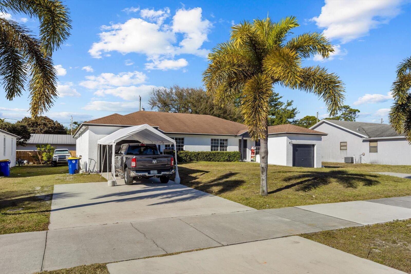 A single-story house with a white exterior, a carport, and a palm tree in front — 2593 SE Indian Street, Stuart FL 34997, STUART, FL