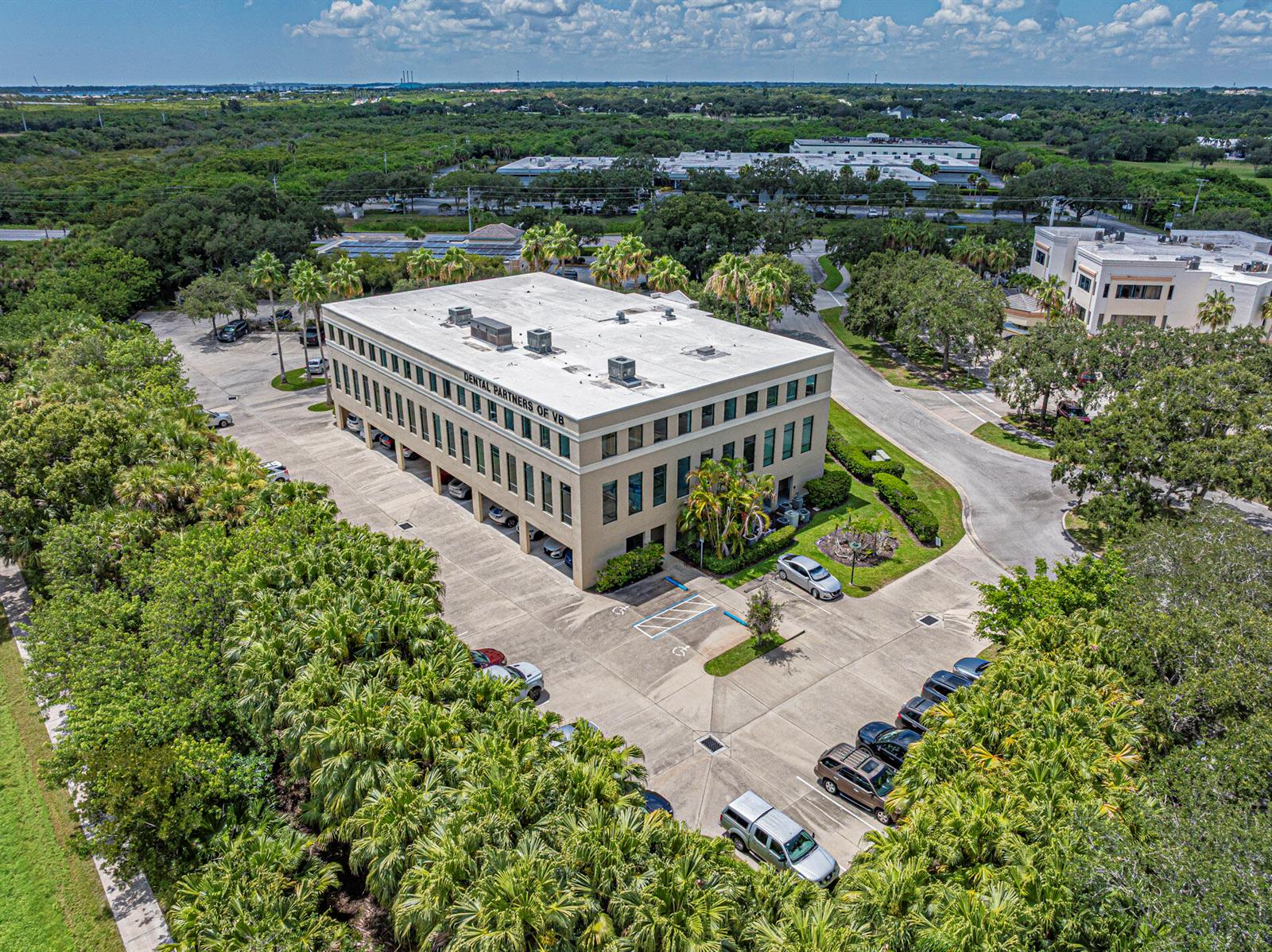 An aerial view shows a multi-story commercial building with a parking lot and surrounding trees — 3755 7th Terrace, Vero Beach FL 32960, VERO BEACH, FL