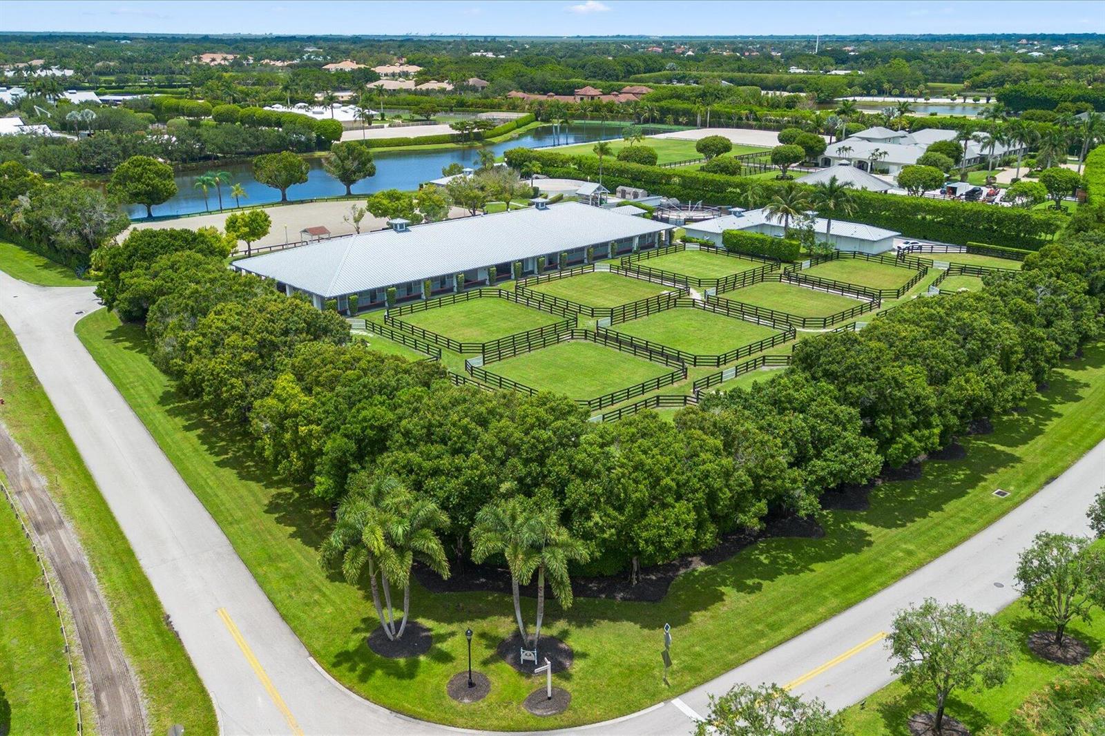 An aerial view shows a large equestrian facility with a stable, fenced paddocks, and landscaping — 3604 Olde Hampton Drive # 1h, Wellington FL 33414, WELLINGTON, FL
