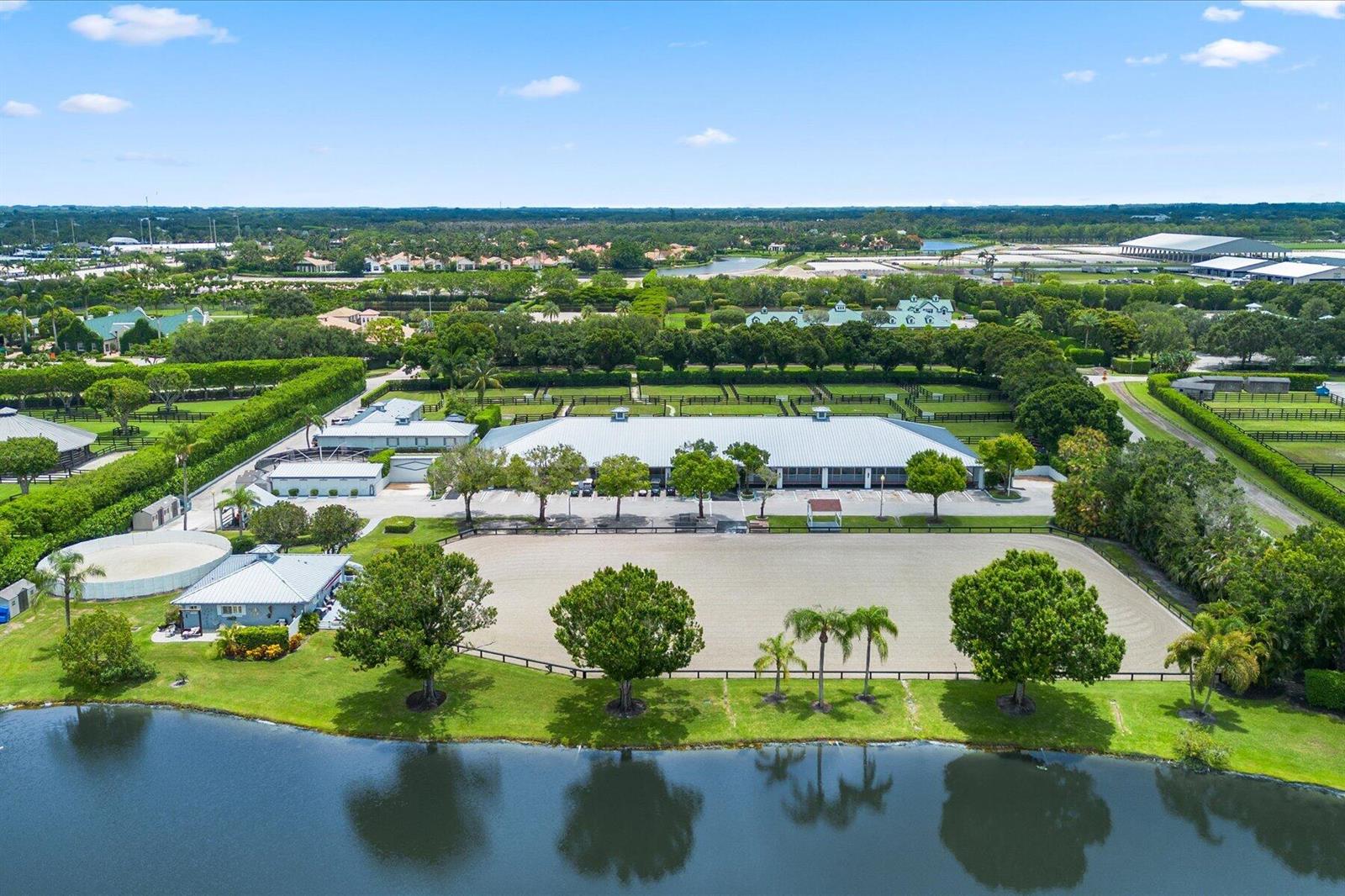 An aerial view shows a large equestrian facility with a riding arena, stables, and pond — 3604 Olde Hampton Drive # 1h, Wellington FL 33414, WELLINGTON, FL