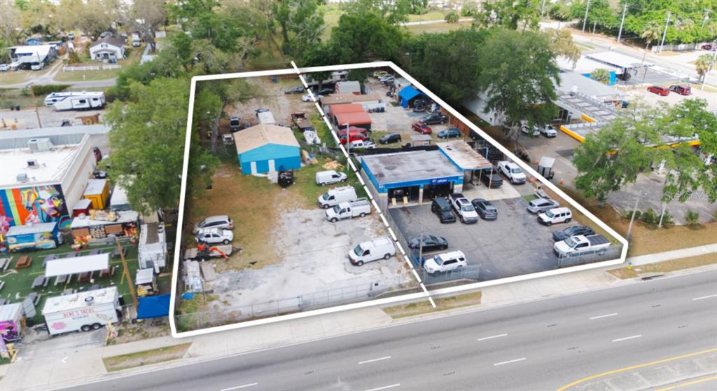 An aerial view shows two adjacent commercial lots with buildings, parking, and vehicles — 6923 W HILLSBOROUGH AVENUE, TAMPA, FL