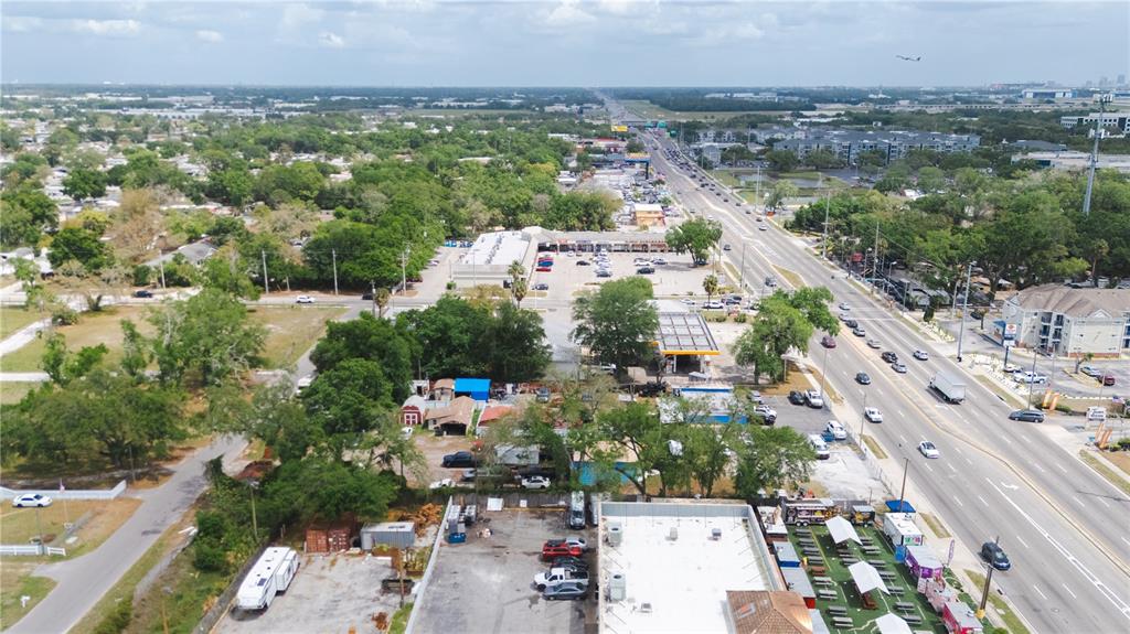 An aerial view shows a commercial strip, a gas station, and a road with traffic — 6923 W HILLSBOROUGH AVENUE, TAMPA, FL