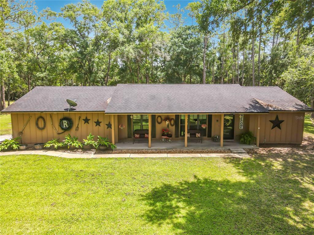 A single-story house with brown vertical siding and a covered front porch faces a lawn — 1395 MAYTOWN ROAD, OSTEEN, FL