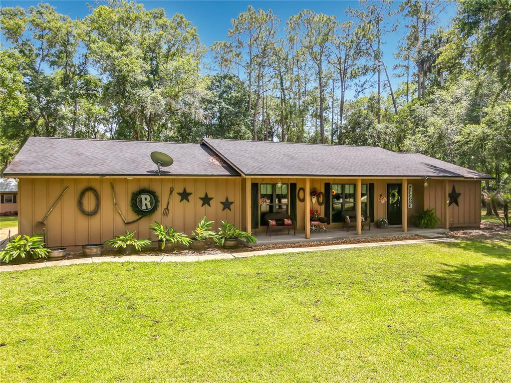 A single-story house with brown vertical siding, a covered porch, and decorative wall accents — 1395 MAYTOWN ROAD, OSTEEN, FL