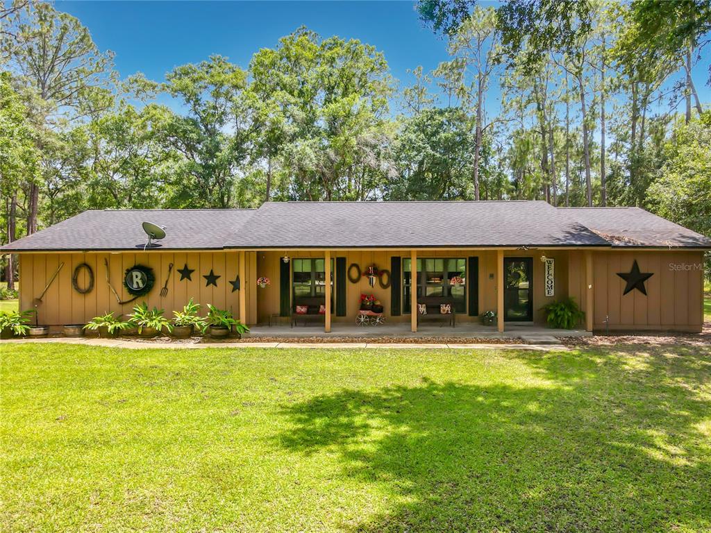 A single-story house with brown vertical siding, a covered front porch, and a large lawn — 1395 MAYTOWN ROAD, OSTEEN, FL