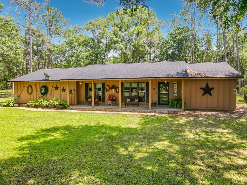 A single-story house with tan siding, a covered front porch, and a large black star — 1395 MAYTOWN ROAD, OSTEEN, FL