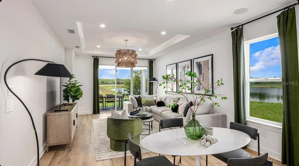 A living and dining area features a tray ceiling, wood flooring, and views of water — 4463 OCHOS RIOS PLACE, KISSIMMEE, FL