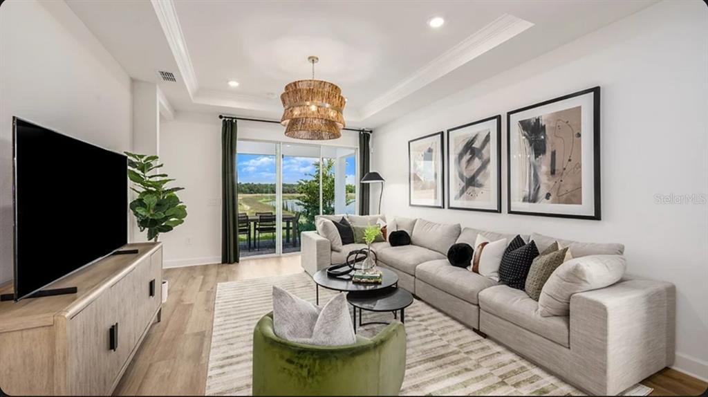 A living room features a sectional sofa, a green armchair, and a view of water — 4463 OCHOS RIOS PLACE, KISSIMMEE, FL