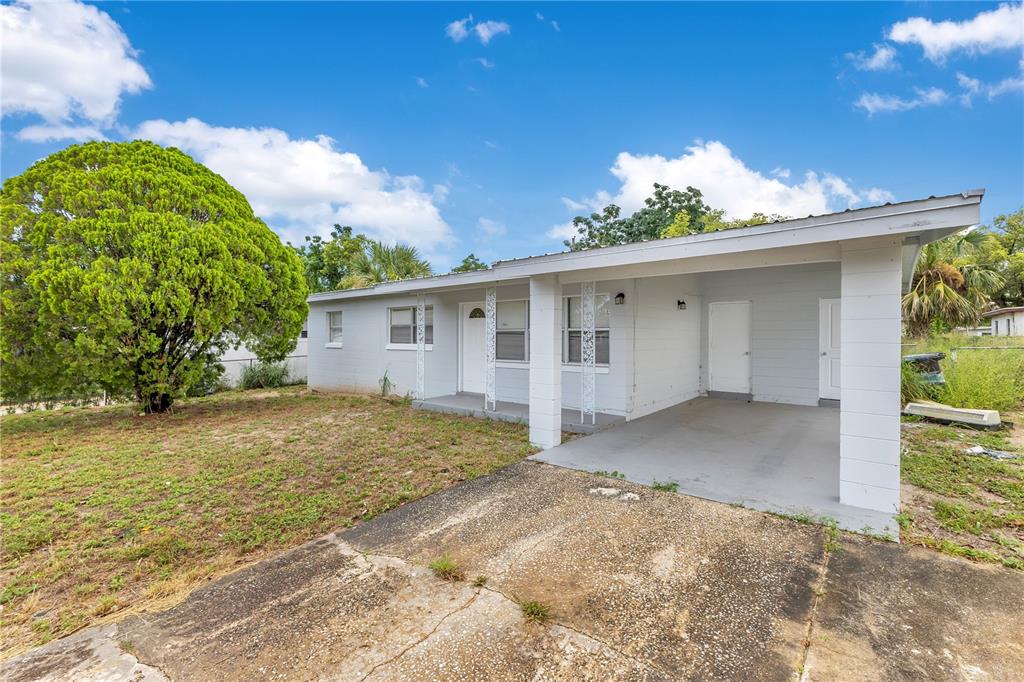 A single-story house with a light gray exterior, a front carport, and a large tree — 6132 W LIVINGSTON STREET, ORLANDO, FL