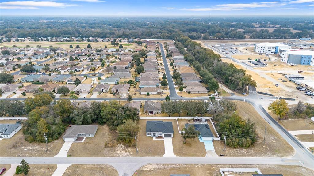 An aerial view shows a suburban neighborhood with houses, streets, and a nearby construction site — 16367 SW 16TH COURT, OCALA, FL