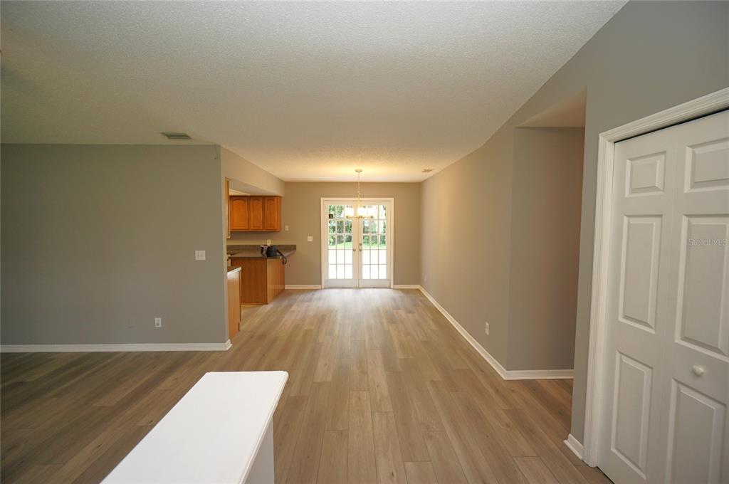 A dining area with light wood-look flooring, gray walls, and glass French doors leading outside — 6005 CHRISTY LANE, RIVERVIEW, FL