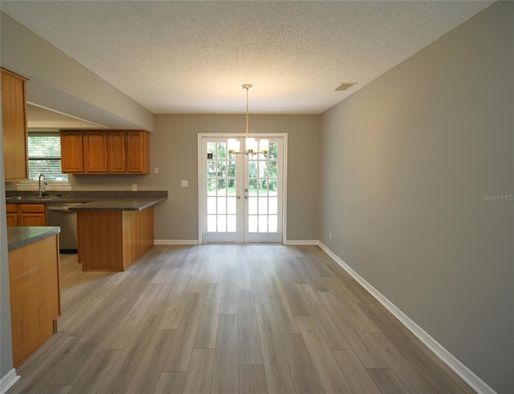A dining area features light wood-look flooring, gray walls, and French doors leading outside — 6005 CHRISTY LANE, RIVERVIEW, FL