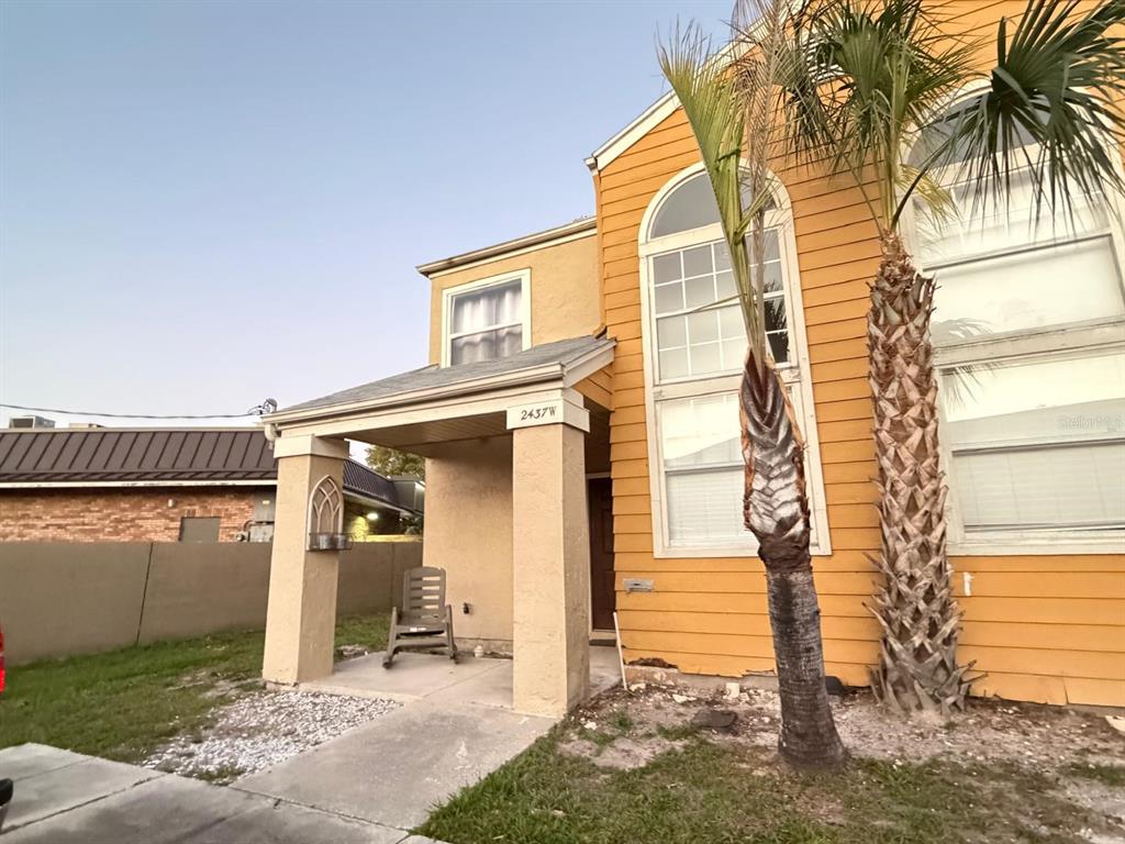 A two-story house with yellow siding, a covered front porch, and two palm trees — 2437 SUMMERFIELD WAY, KISSIMMEE, FL