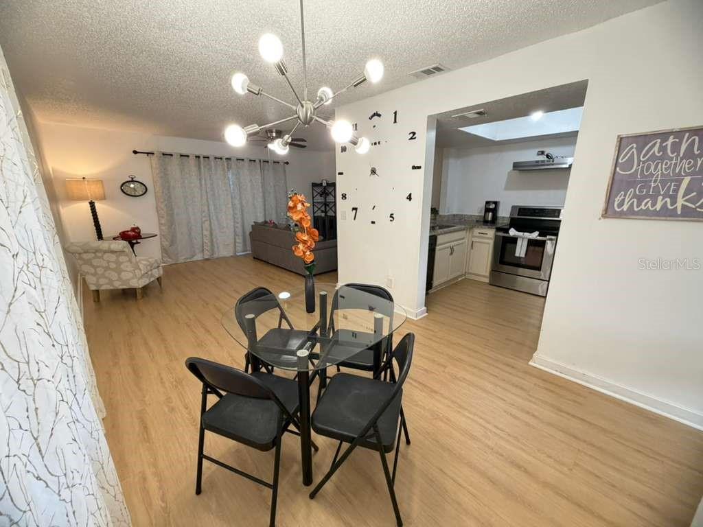 A dining area with a glass table and chairs sits in front of an open kitchen — 2437 SUMMERFIELD WAY, KISSIMMEE, FL