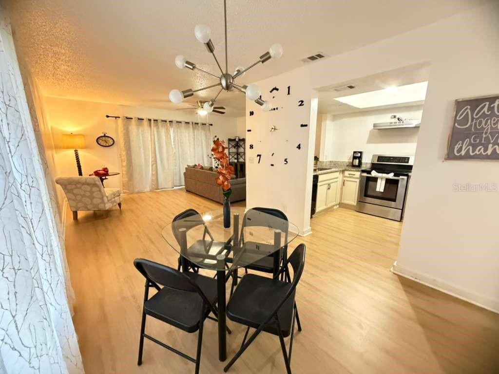 A dining area with a glass table and chairs sits in front of an open kitchen — 2437 SUMMERFIELD WAY, KISSIMMEE, FL