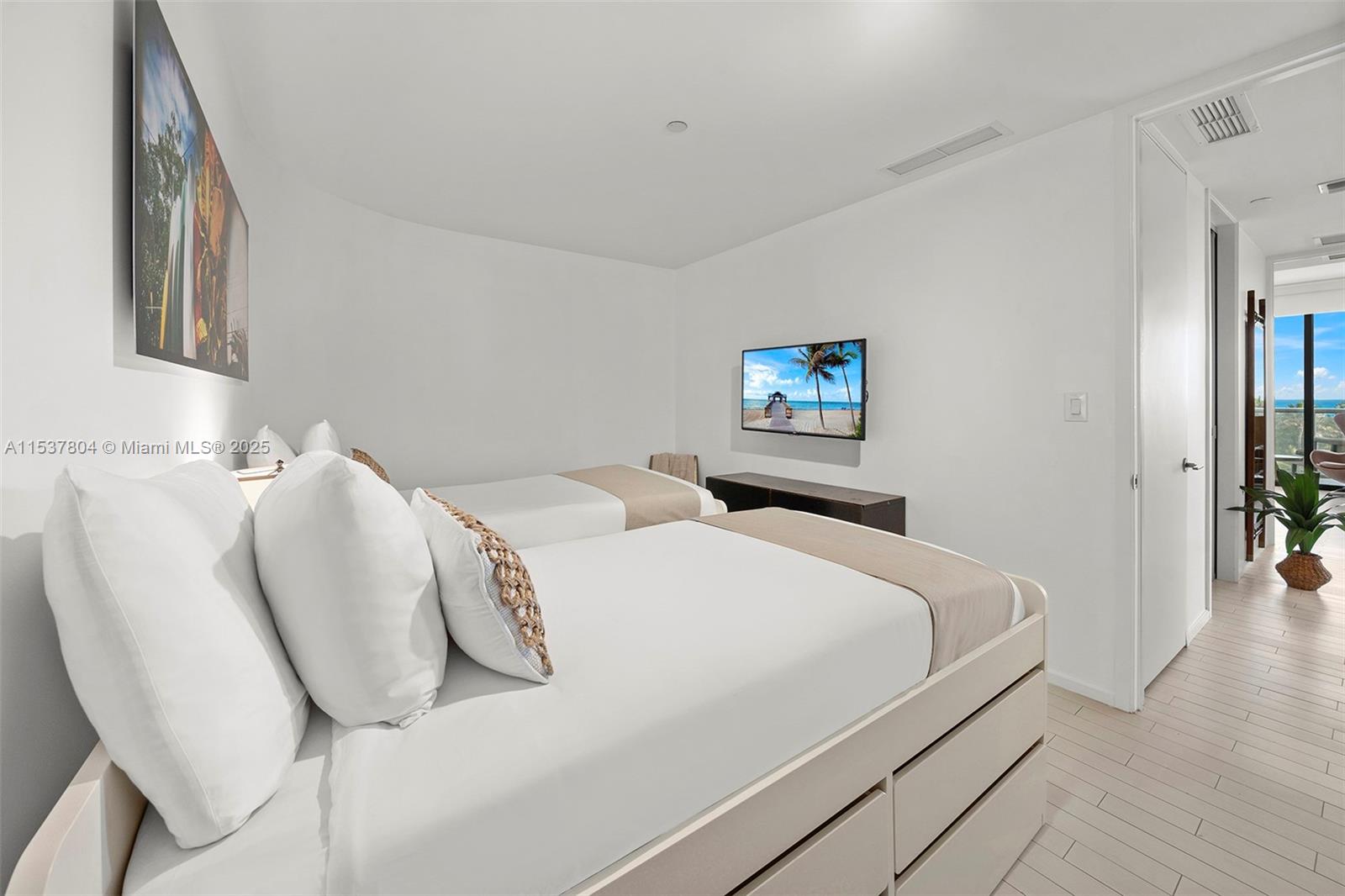 A bedroom features two beds, a wall-mounted television, and a balcony with ocean views — 2201 Collins Ave # 814, Miami Beach FL 33139, MIAMI BEACH, FL