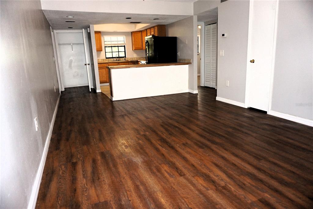 An outdoor covered walkway with textured peach walls, black railings, and a white entry door — 12900 VONN ROAD UNIT B201, LARGO, FL