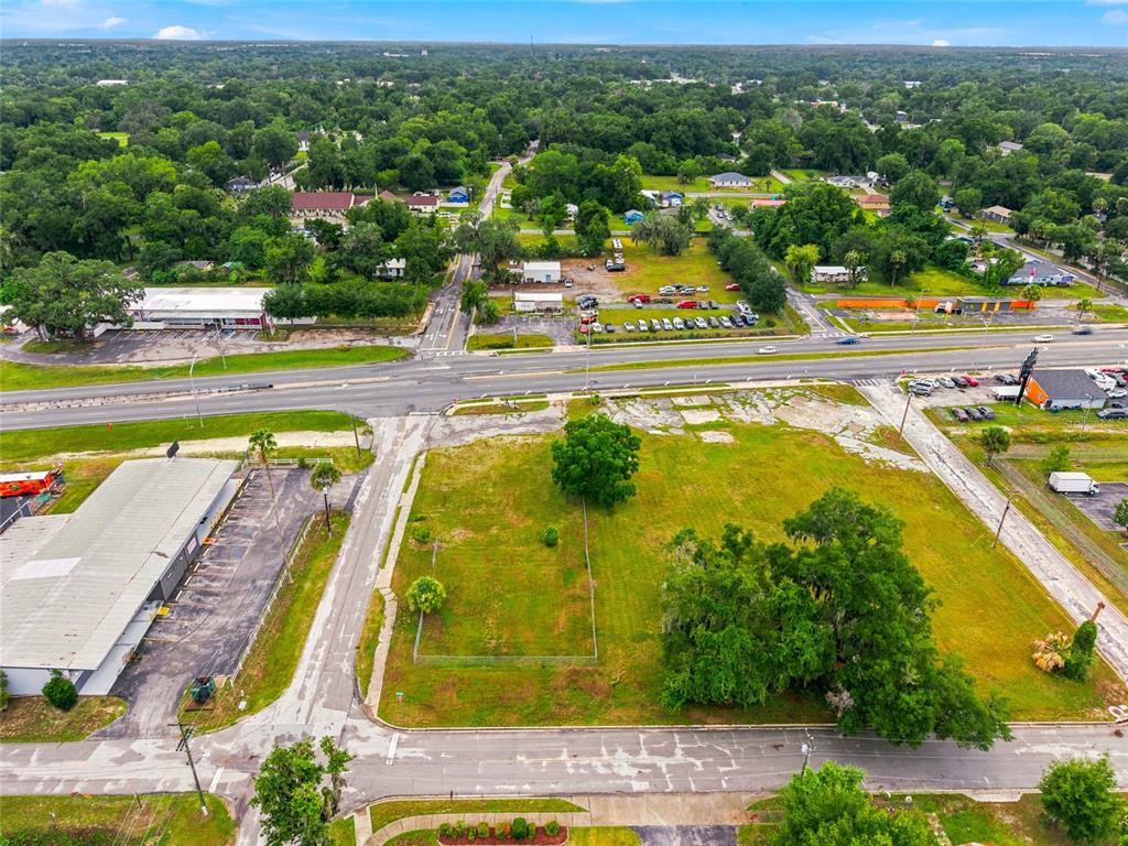 An aerial view shows a vacant grassy lot bordered by roads and commercial buildings — 409 NW 8TH STREET, OCALA, FL
