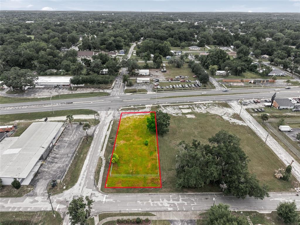 An aerial view shows a rectangular vacant lot outlined in red next to a paved road — 409 NW 8TH STREET, OCALA, FL