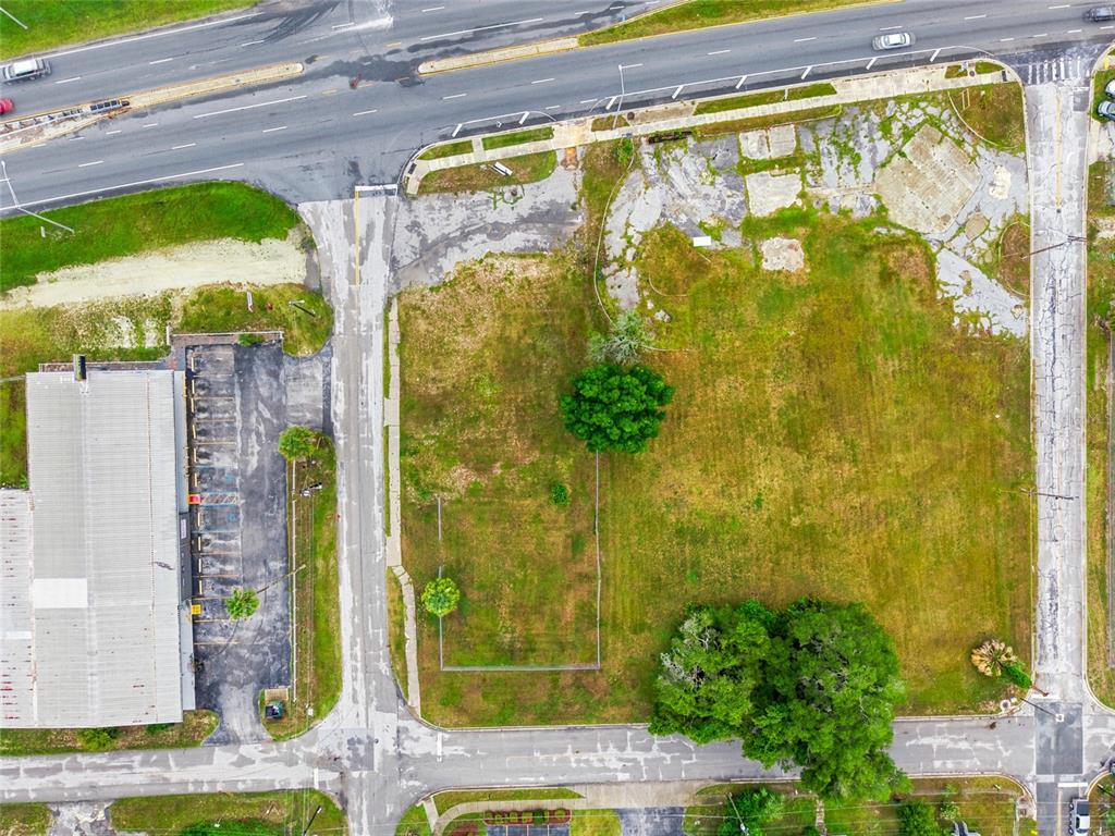 An aerial view shows a vacant, grassy lot bordered by paved roads and a building — 409 NW 8TH STREET, OCALA, FL