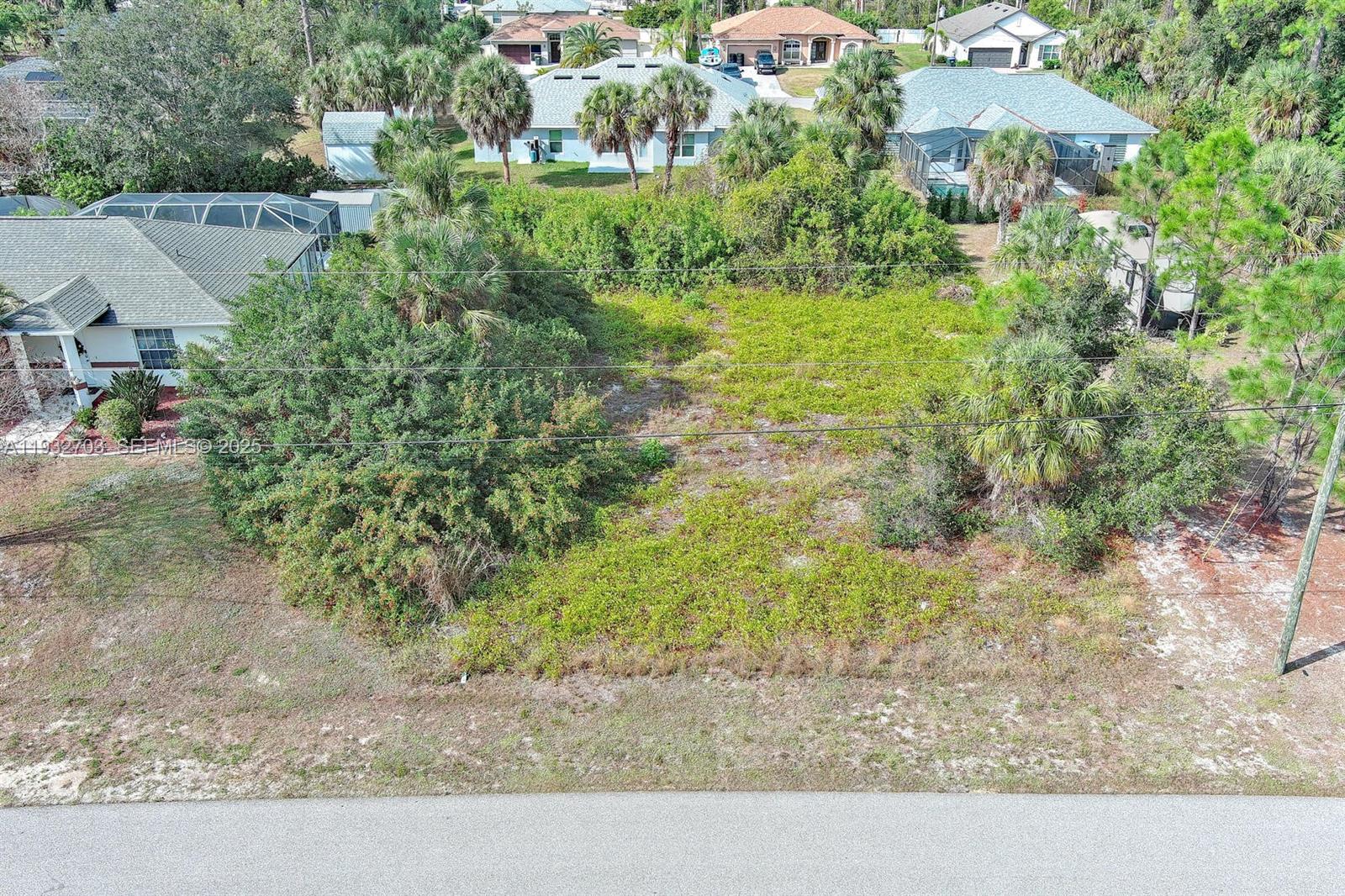 An aerial view shows a vacant, overgrown residential lot situated between existing houses — 0 SADNET LN, North Port FL 34286, NORTH PORT, FL