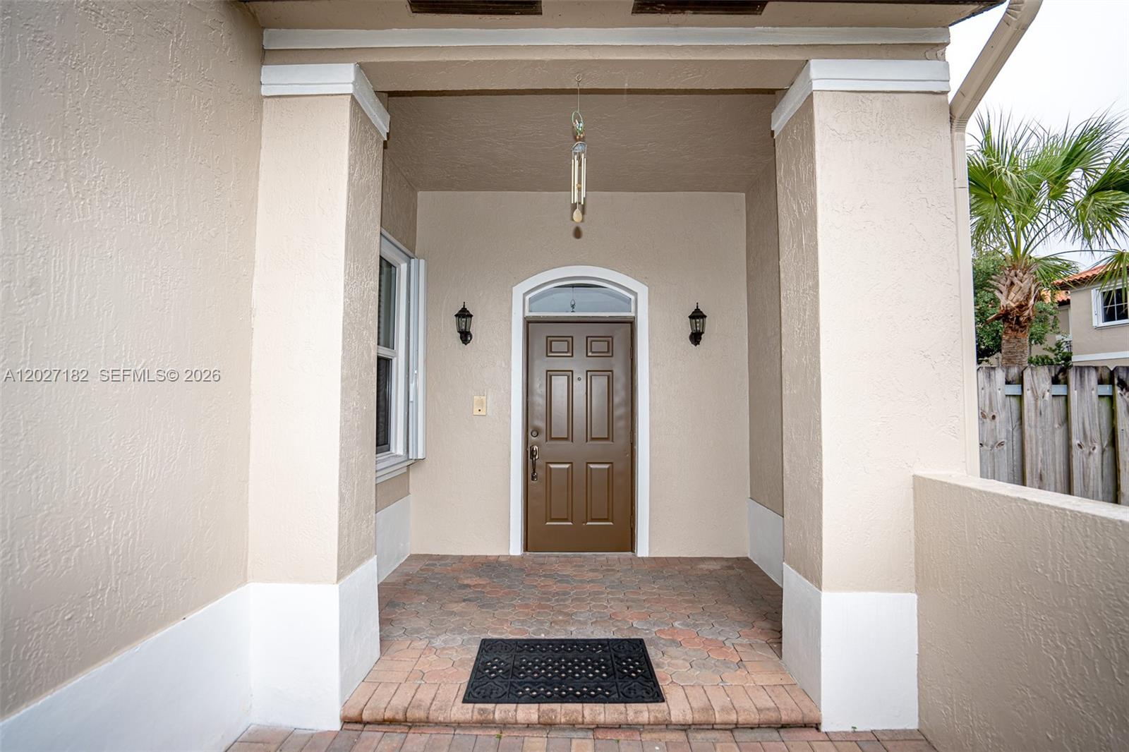 A brown front door is centered under a covered porch with beige stucco walls — 14372 NW 83rd Ave, Miami Lakes FL 33016, MIAMI LAKES, FL