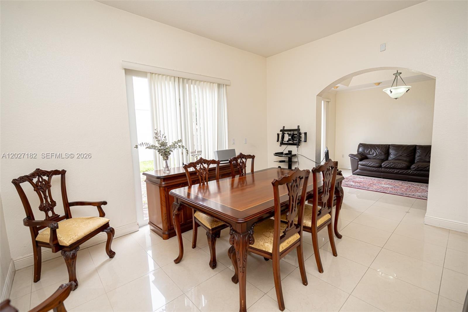 A dining room with a wooden table and chairs sits adjacent to a living area — 14372 NW 83rd Ave, Miami Lakes FL 33016, MIAMI LAKES, FL
