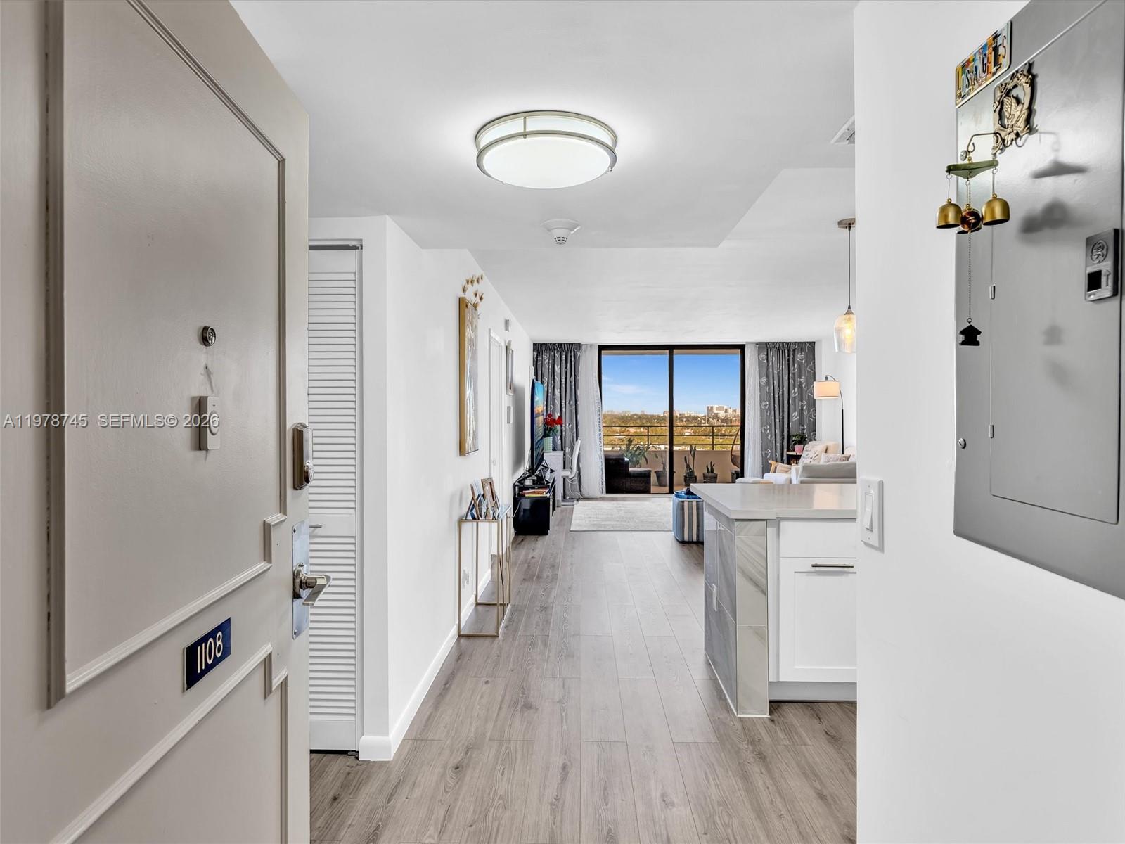 An entryway leads into a bright living area with wood-look flooring and a balcony view — 2500 Parkview Dr # 1108, Hallandale Beach FL 33009, HALLANDALE BEACH, FL