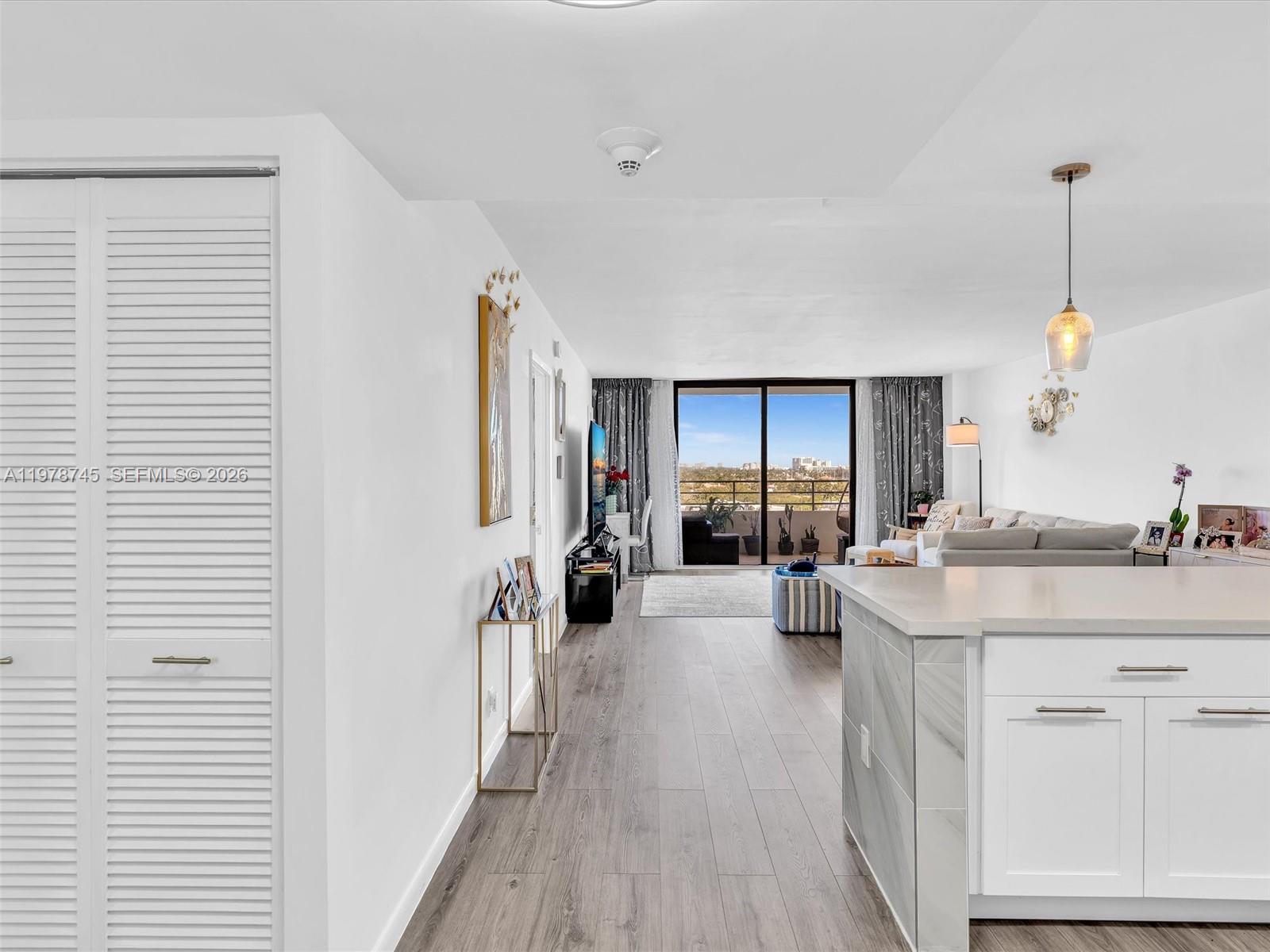 A bright living area features wood-look flooring, a kitchen island, and a balcony with views — 2500 Parkview Dr # 1108, Hallandale Beach FL 33009, HALLANDALE BEACH, FL