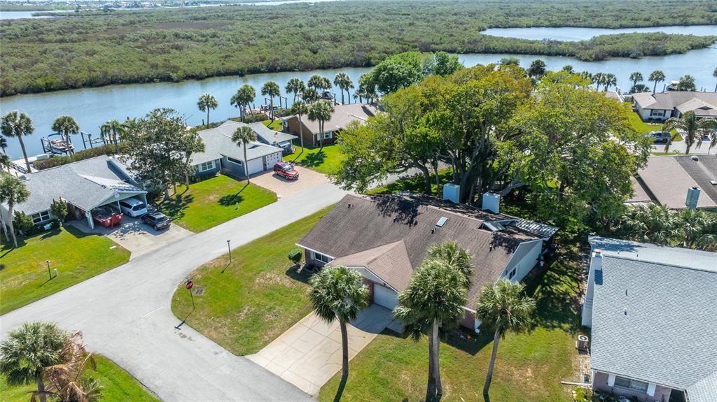 An aerial view shows suburban houses with palm trees near a canal and marshland — 1400 PORTOBELLO DRIVE, PORT ORANGE, FL