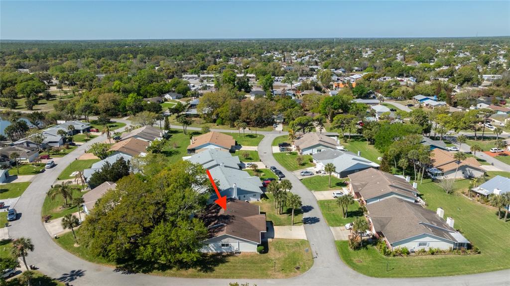 An aerial view shows a residential neighborhood with a red arrow pointing to a house — 1400 PORTOBELLO DRIVE, PORT ORANGE, FL