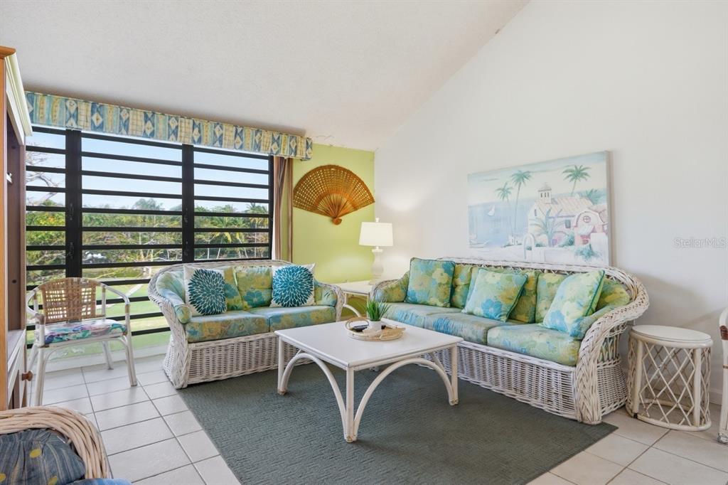 A living room with white wicker furniture, a green area rug, and large window views — 1 BEACH VILLAGE DRIVE UNIT 92, HUMACAO, PR