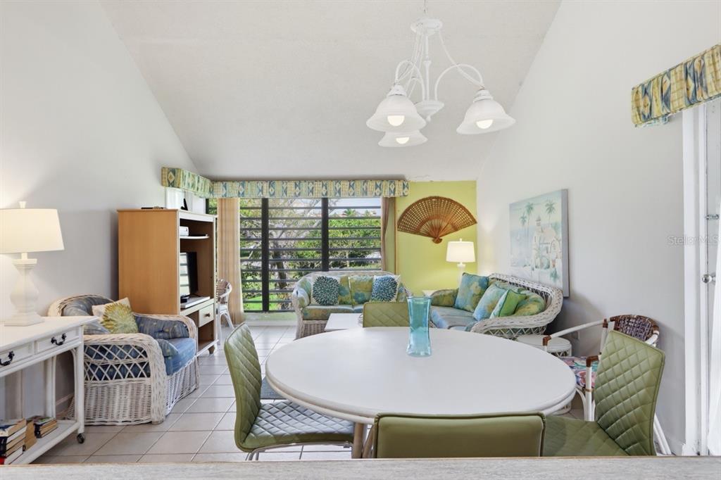A living and dining area with wicker furniture, a round table, and large windows — 1 BEACH VILLAGE DRIVE UNIT 92, HUMACAO, PR