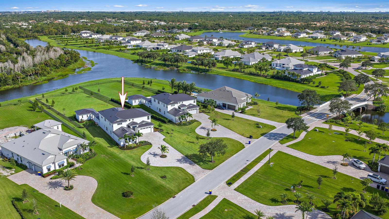 An aerial view shows a modern white house with a dark roof near a lake — 20037 SE Bridgewater Drive, Jupiter FL 33458, JUPITER, FL