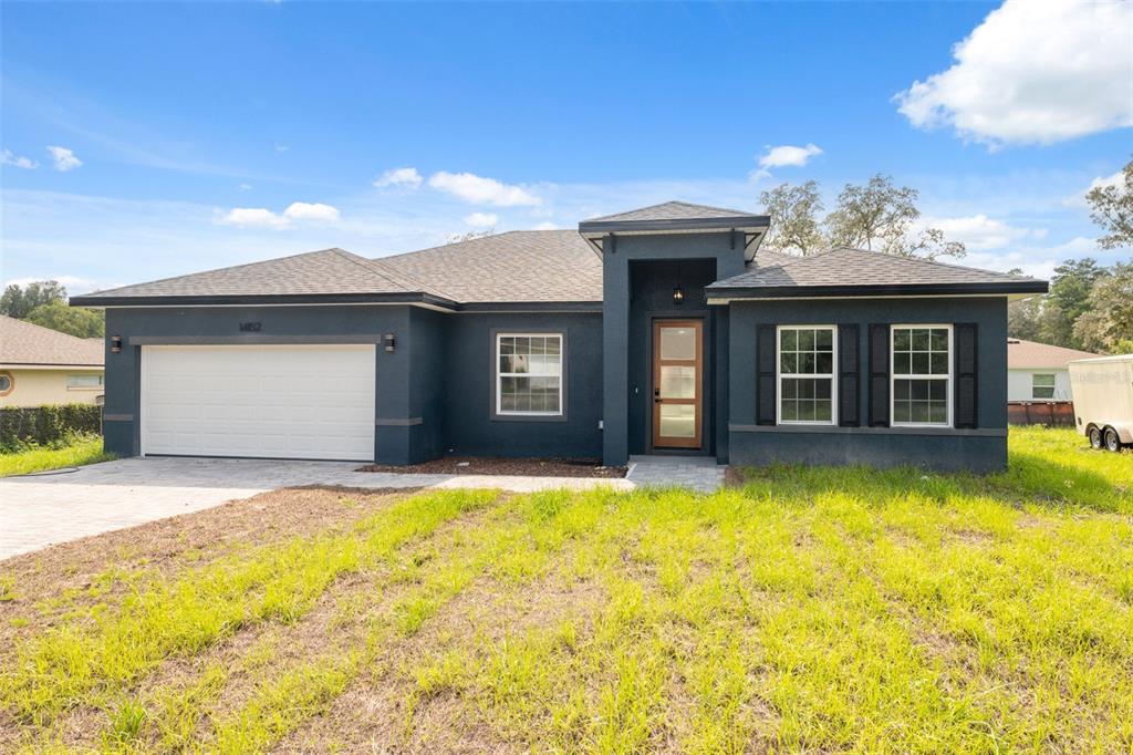 A dark blue, single-story suburban house with a two-car garage and a paved driveway — 14152 SW 44TH AVENUE, OCALA, FL