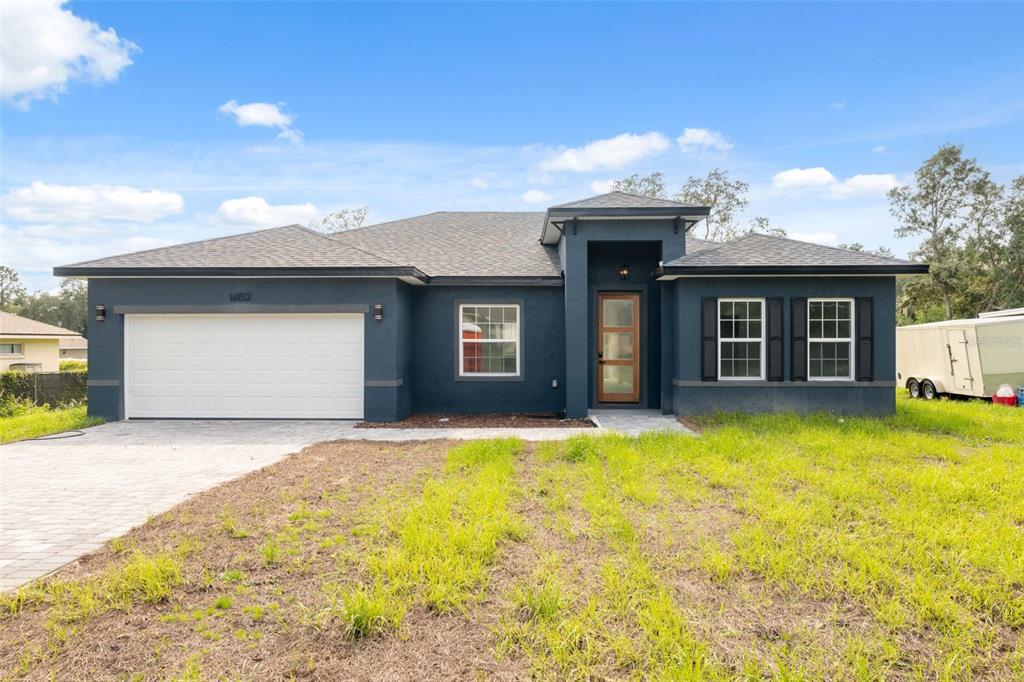 A dark blue, single-story house with a two-car garage and a paved driveway — 14152 SW 44TH AVENUE, OCALA, FL