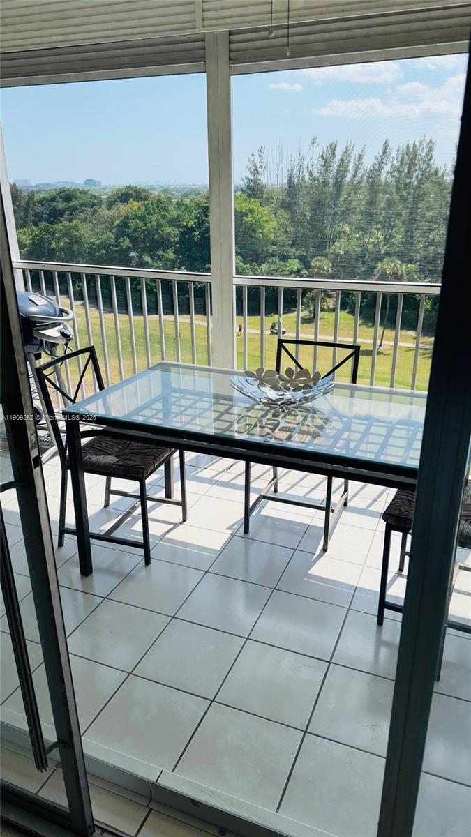 A glass-topped dining table and chairs sit on a screened balcony overlooking a golf course — 3150 N Palm Aire Dr # 801, Pompano Beach FL 33069, POMPANO BEACH, FL