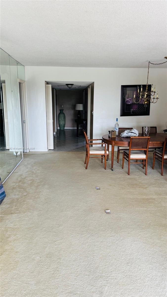 A dining area with a wooden table and chairs sits adjacent to a carpeted living space — 3150 N Palm Aire Dr # 801, Pompano Beach FL 33069, POMPANO BEACH, FL