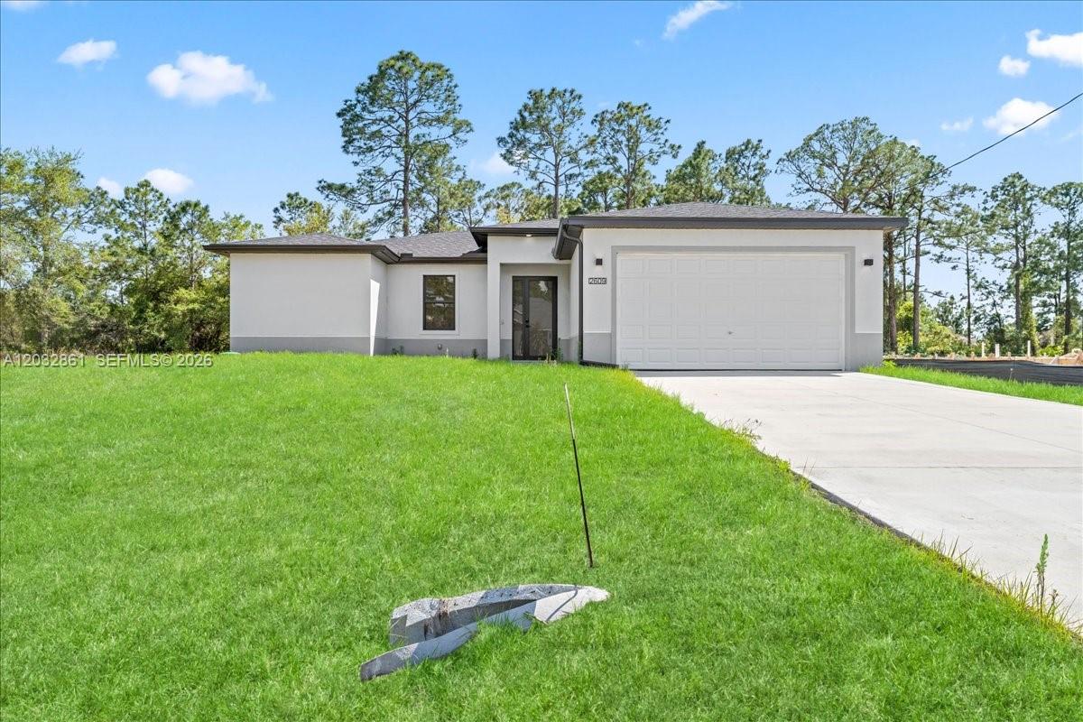 A single-story house with a white exterior, a two-car garage, and a concrete driveway — 2609 53rd st w, Lehigh Acres FL 33971, LEHIGH ACRES, FL