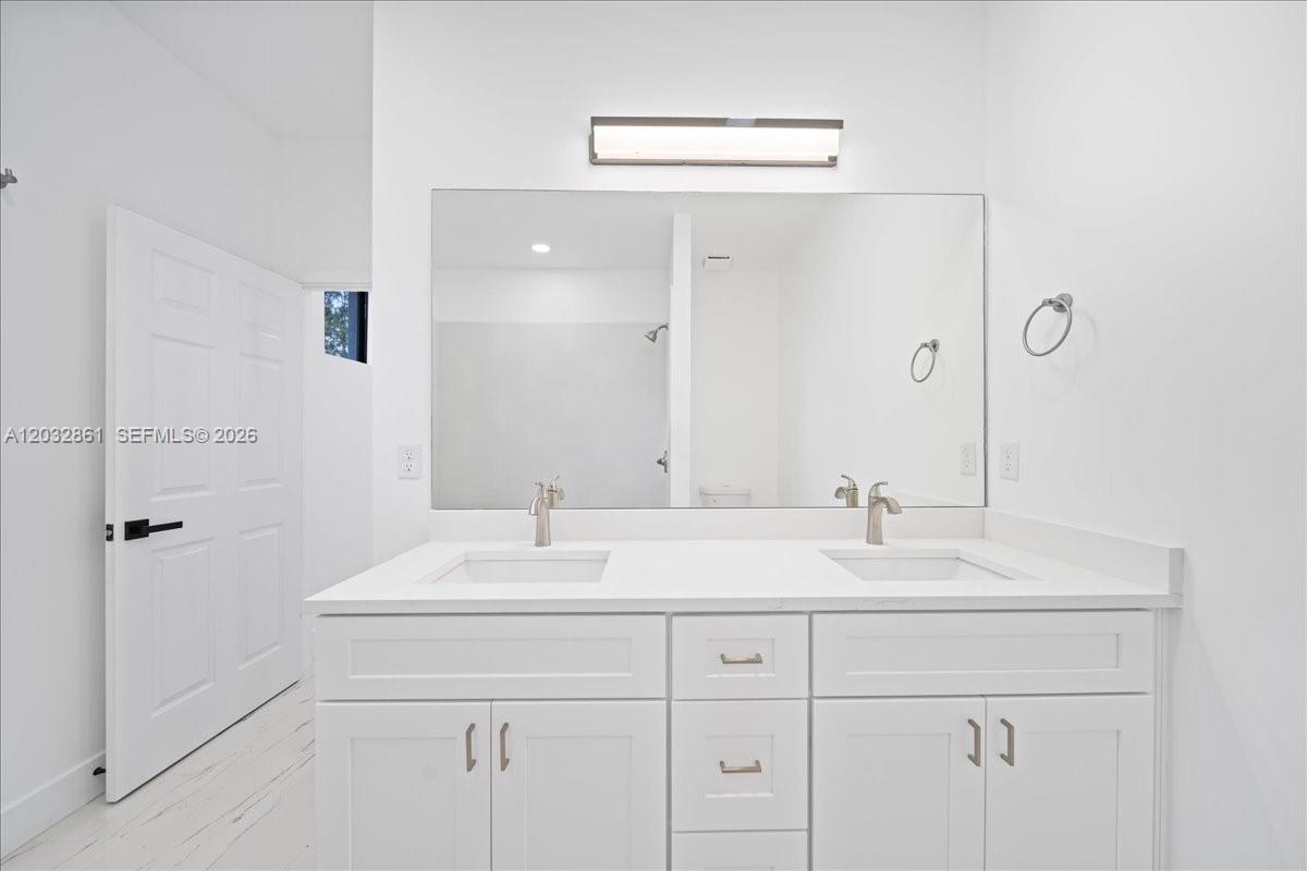 A modern bathroom features a white double vanity with two sinks and a large mirror — 2609 53rd st w, Lehigh Acres FL 33971, LEHIGH ACRES, FL