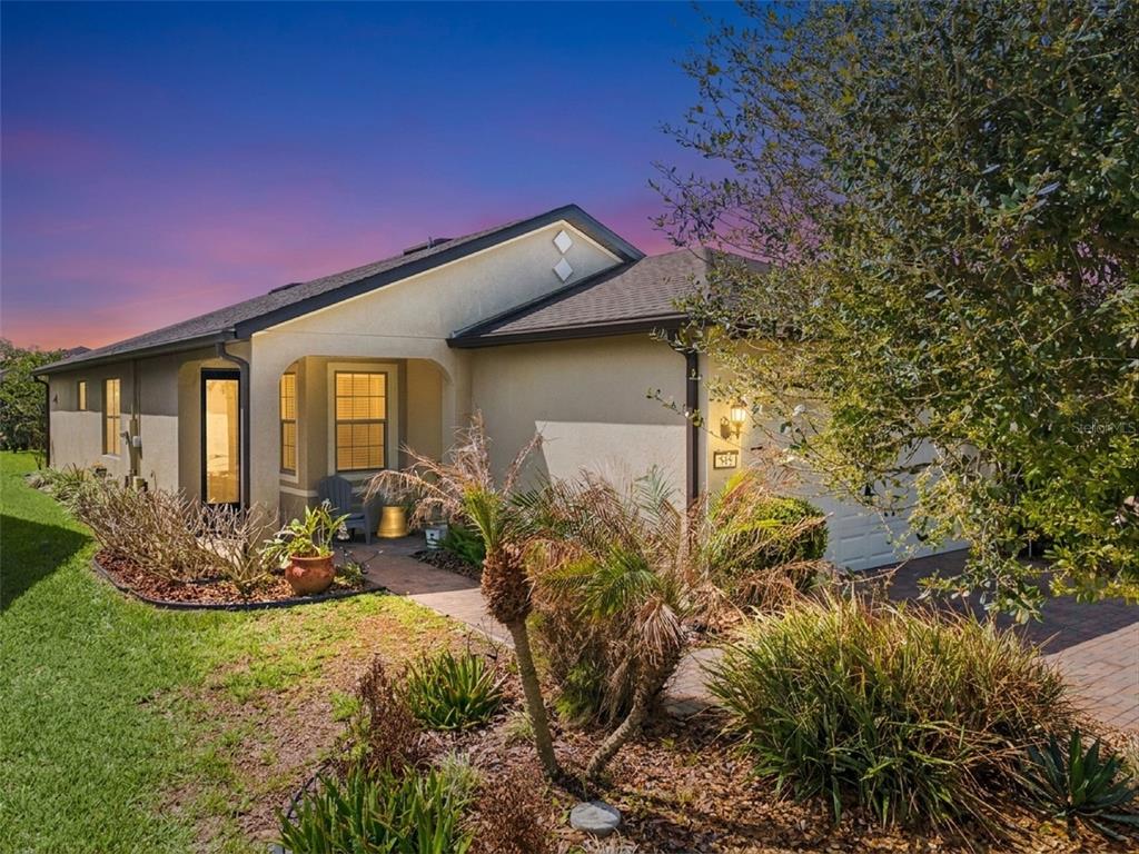 A single-story house with a stucco exterior, a paved walkway, and landscaping at dusk — 545 CANTABRIA DRIVE, DAVENPORT, FL