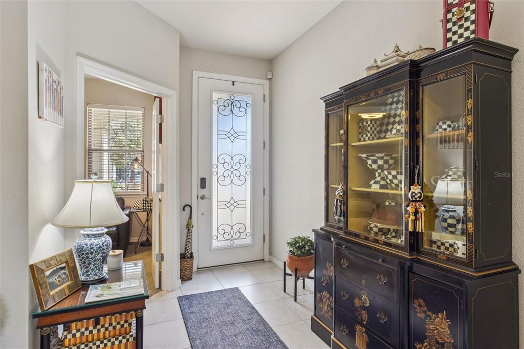 An entryway features a white front door with decorative glass, tile flooring, and a black hutch — 545 CANTABRIA DRIVE, DAVENPORT, FL