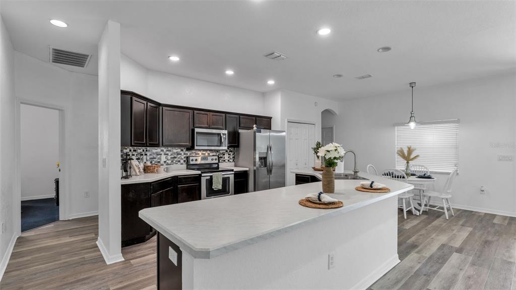 A kitchen features dark wood cabinets, stainless steel appliances, and a white breakfast bar island — 119 GERBER DAIRY ROAD, EAGLE LAKE, FL